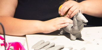 Girl building an animal out of clay