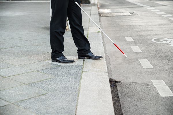 Individual with visual impairment approaching a street curb
